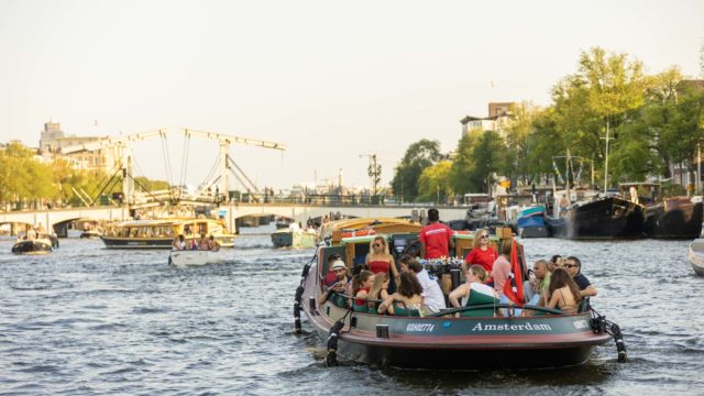 Ein Schlepper mit Menschen auf den Amsterdamer Grachten im Sommer.