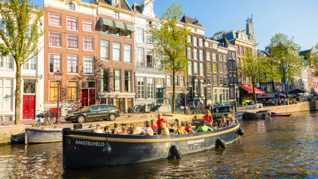 A Mokumboot tugboat with skipper cruising the Amstel River near Amsterdam&rsquo;s iconic Magere Brug.